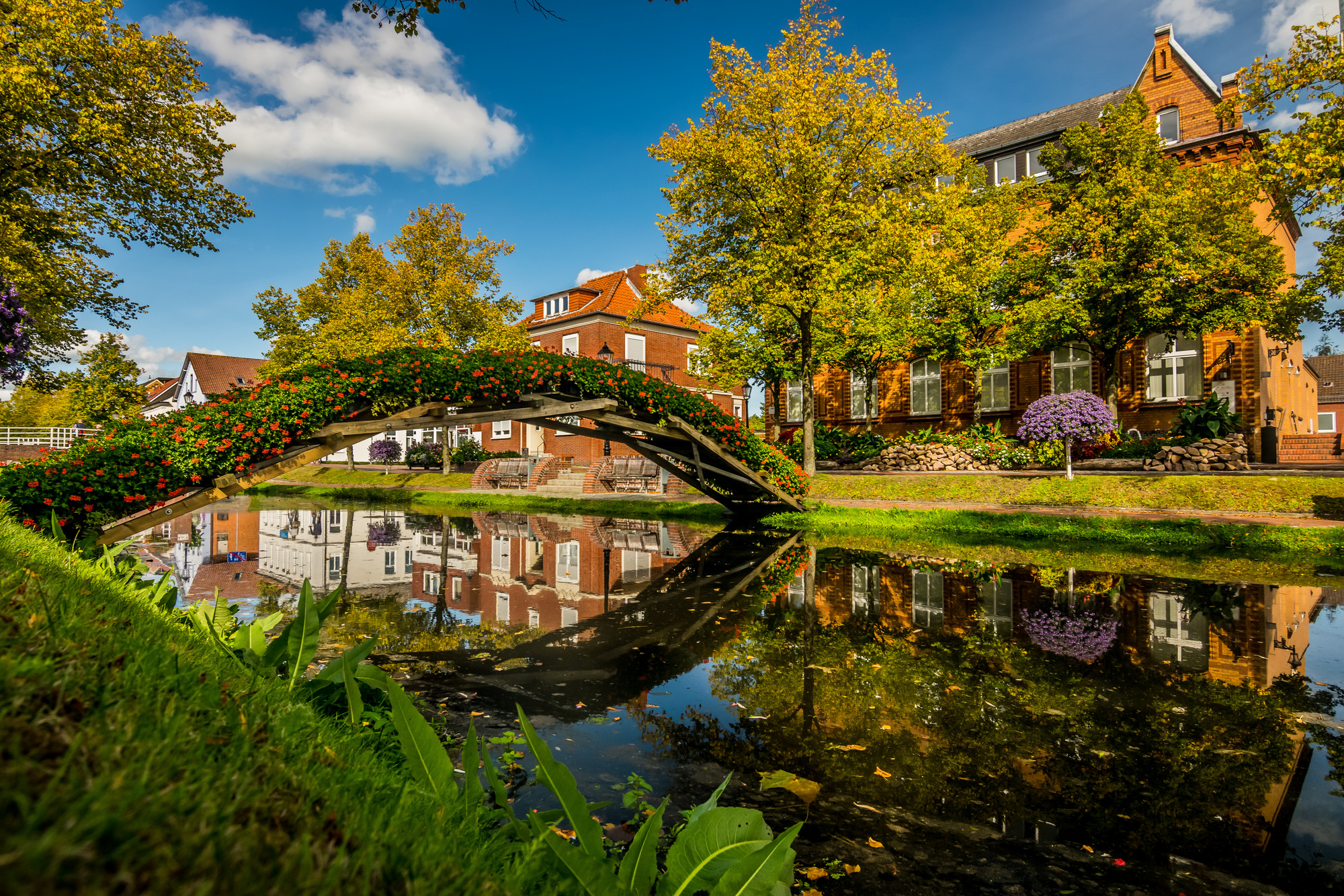 Eine Brücke über einem Kanal in Papenburg mit einem Gebäude im Hintergrund, das die malerische Szenerie ergänzt