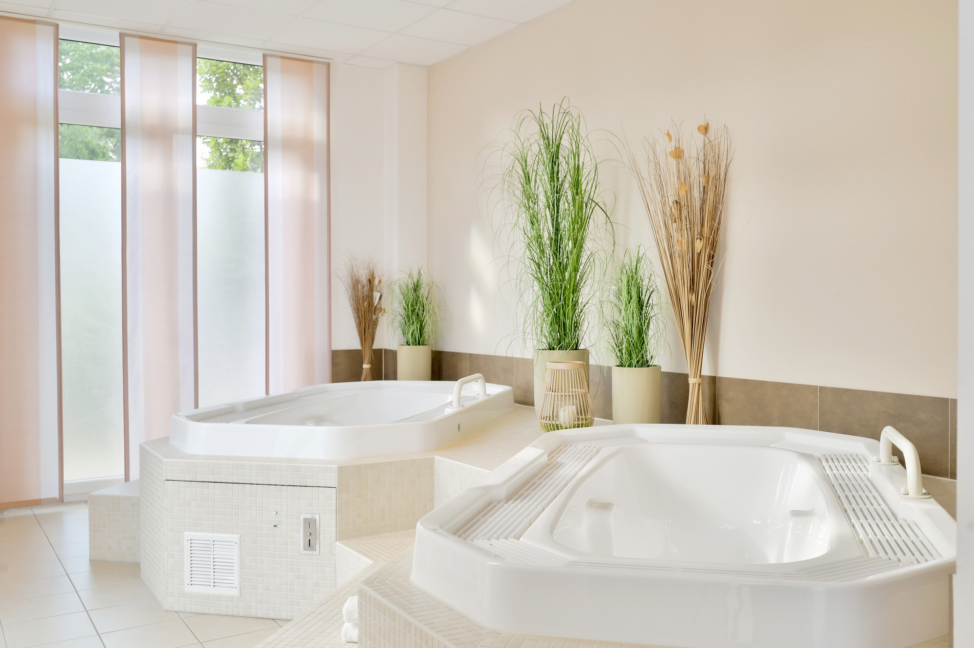 Heller Wellnessbereich mit zwei großen Whirlpool-Badewannen zum Entspannen