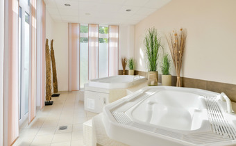 Heller Wellnessbereich mit zwei großen Whirlpool-Badewannen zum Entspannen